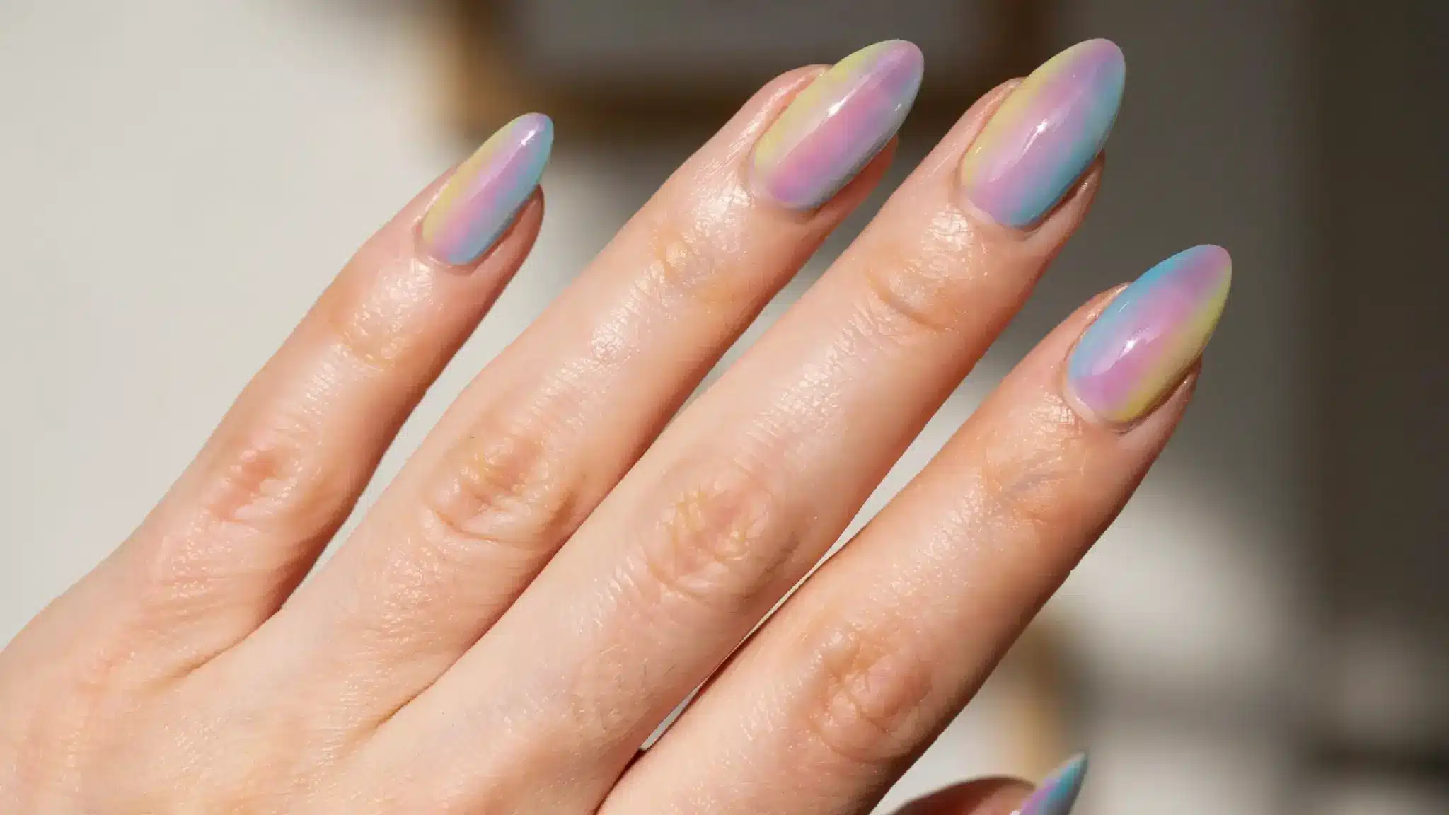 Pastel rainbow gradient nail art with glossy finish on a hand.