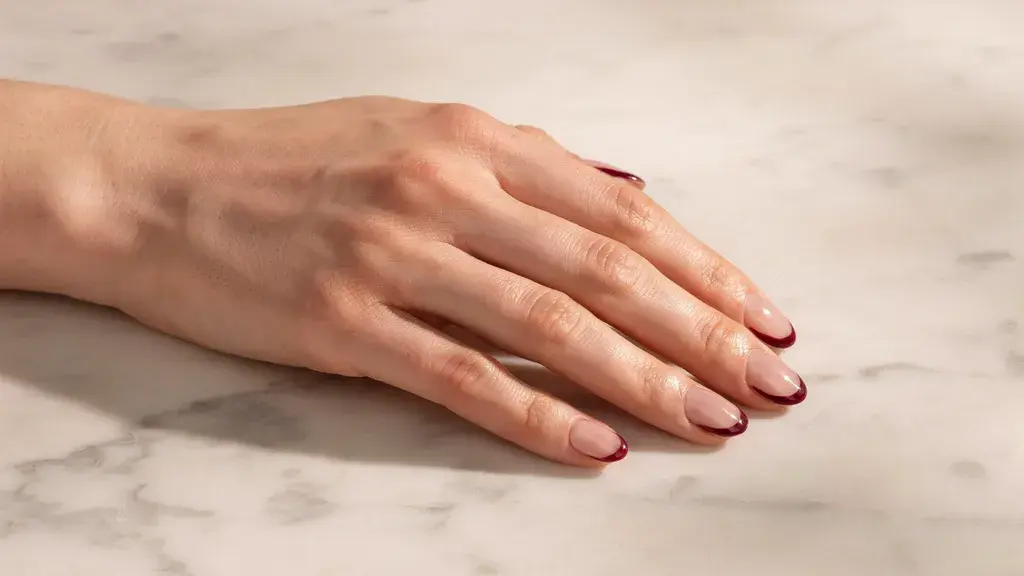 Reverse French nail design featuring glossy nude nails with curved cuticle accents for a simple nail art look