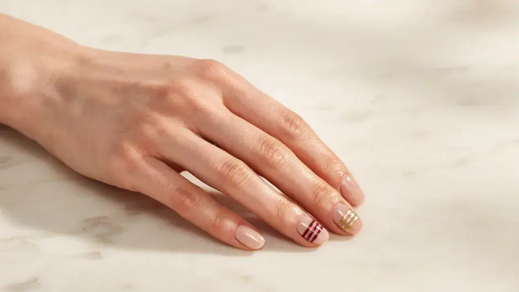 Striped accent nail design featuring glossy nude nails with thin parallel lines for a simple nail art look