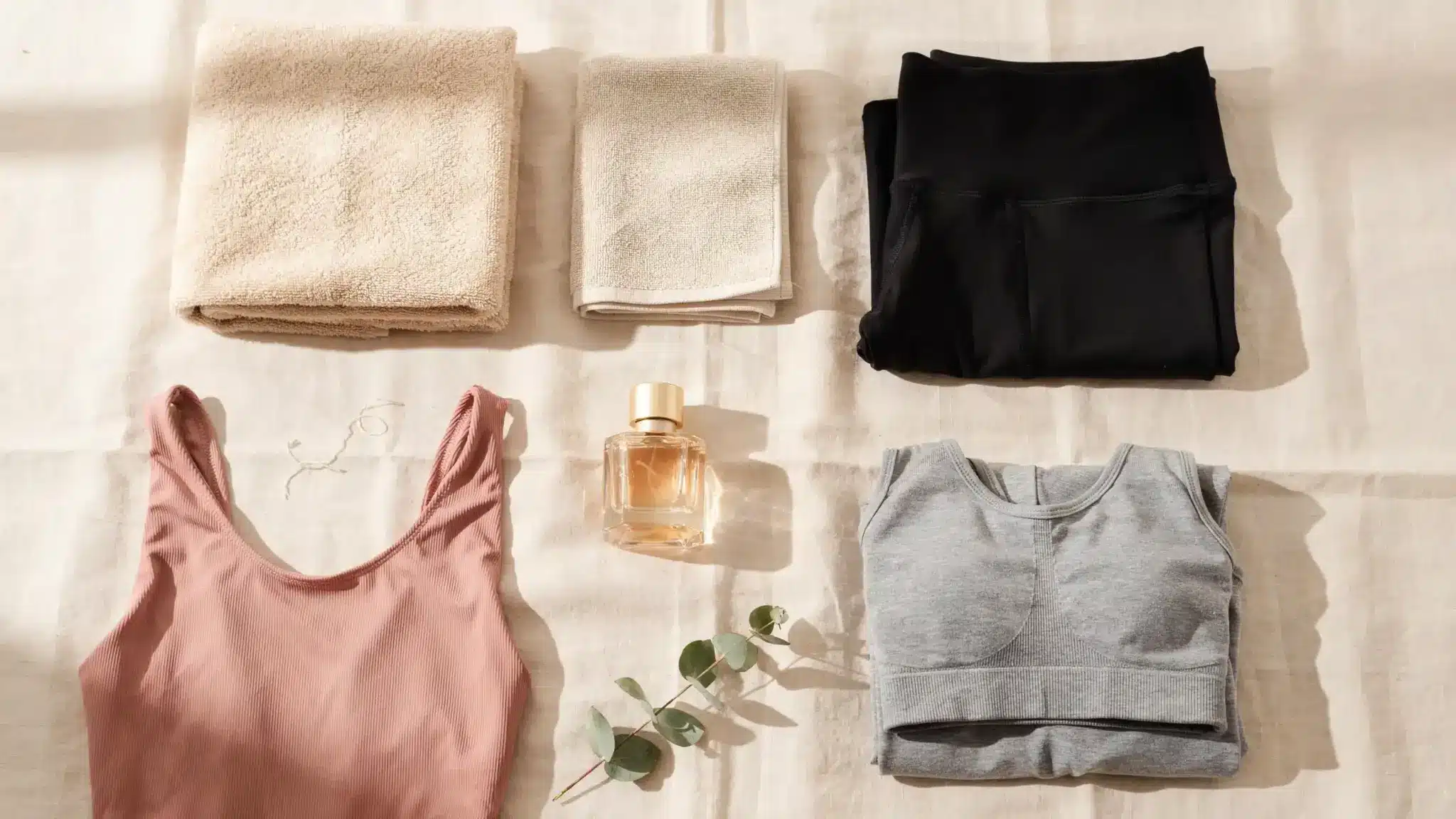 Flat lay of hot towels tight clothing perfume and workout items representing things to avoid after waxing