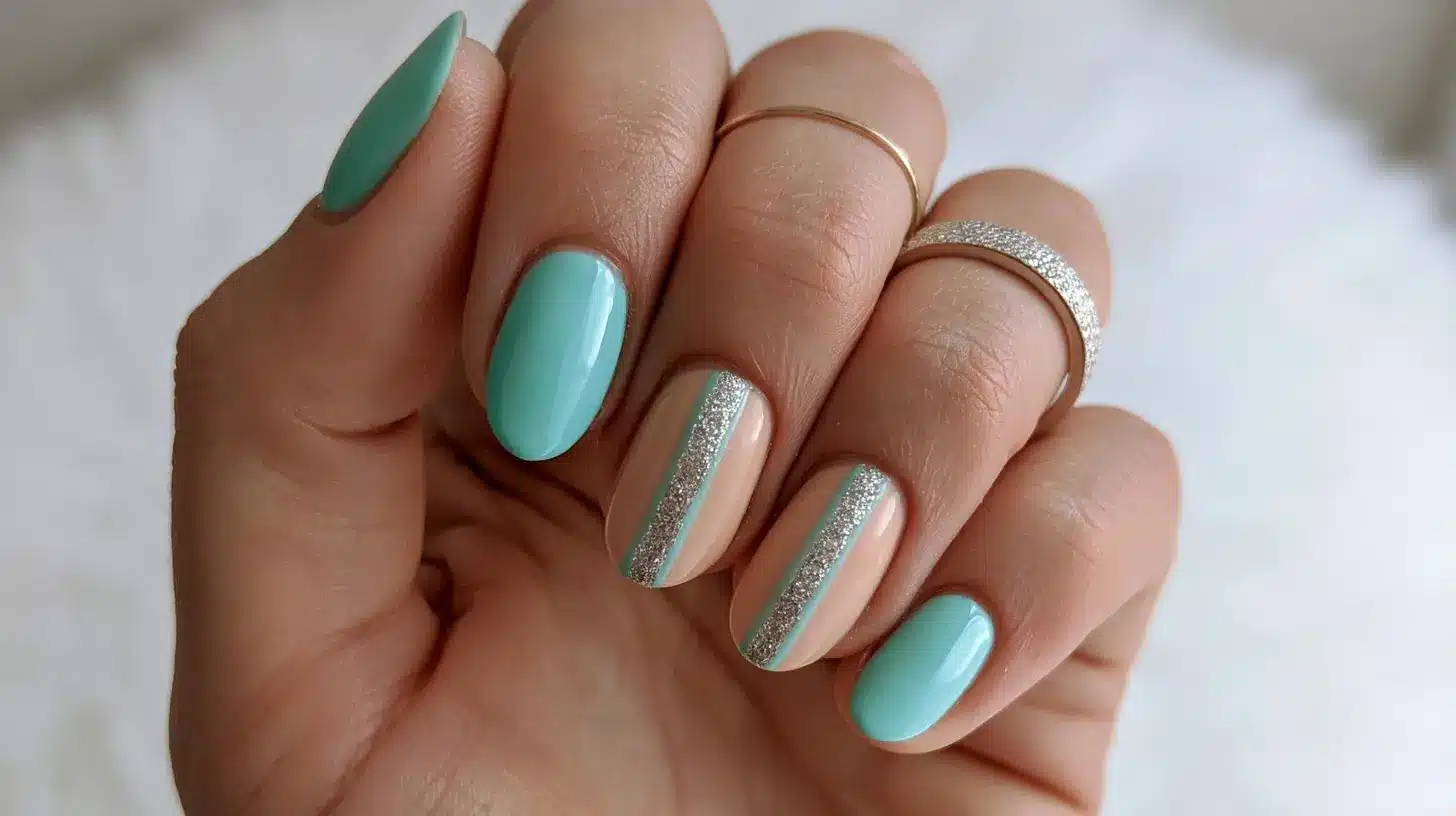 tiffany blue manicure with nude accent nails featuring silver glitter stripes, paired with delicate gold and silver rings.
