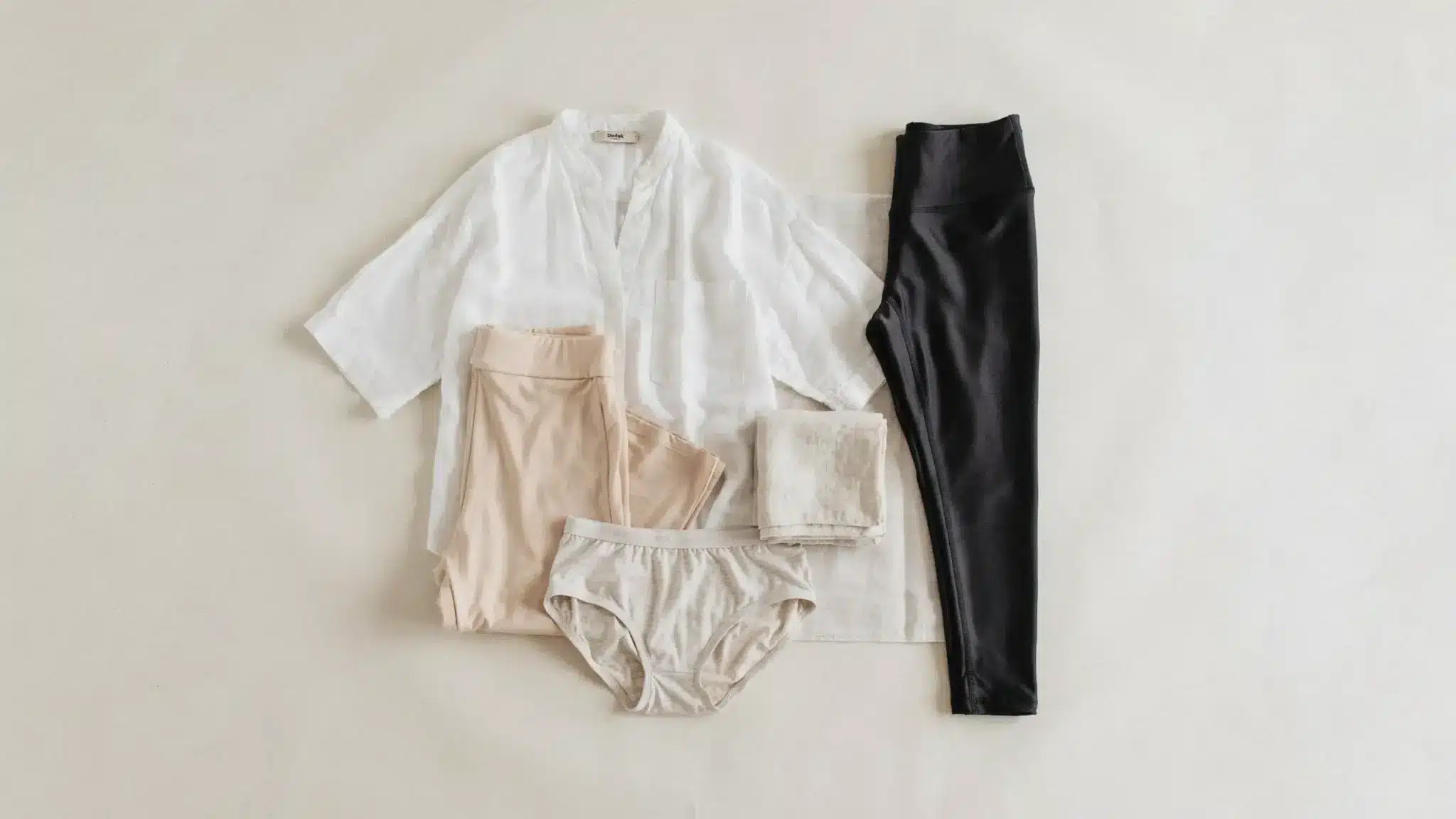 Flat lay showing loose cotton clothing and soft fabrics compared with tight synthetic leggings after waxing care