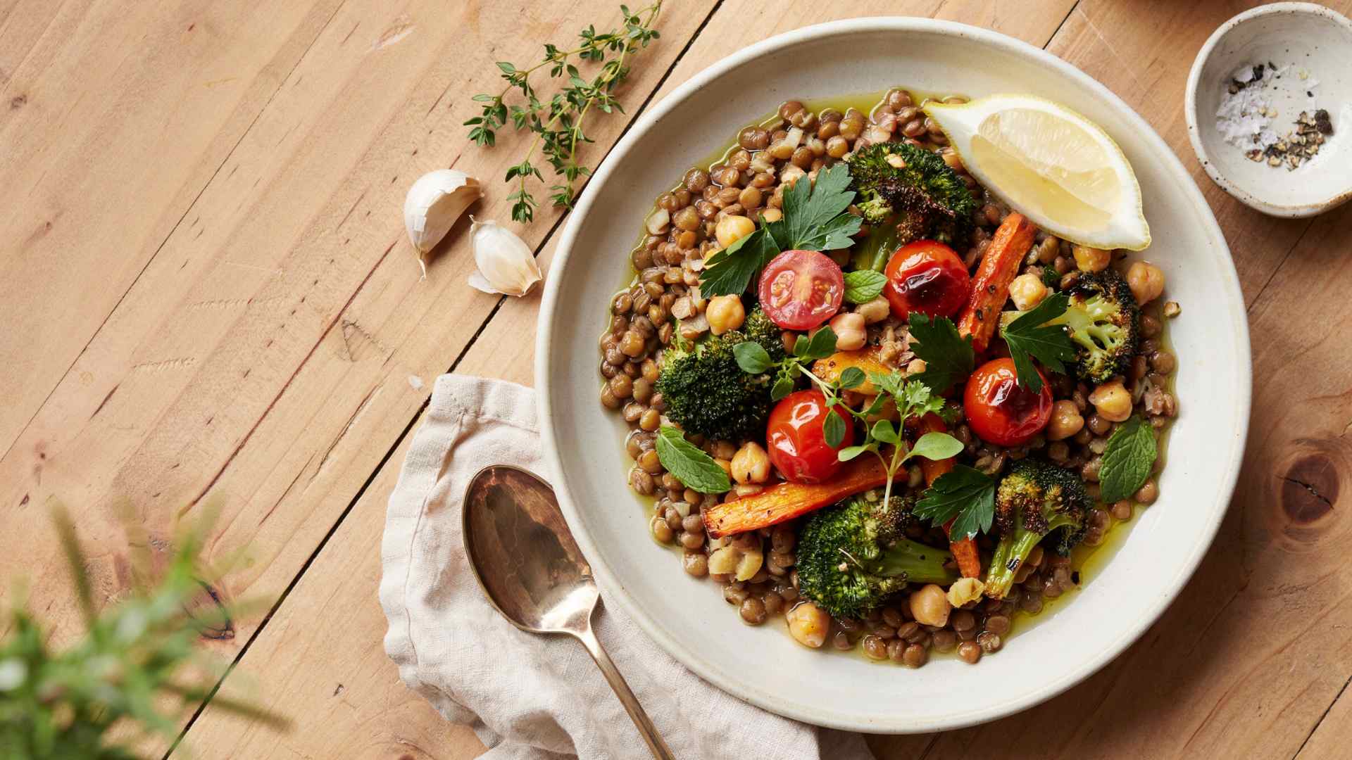 Bowl of cooked lentils topped with roasted vegetables and herbs, a source of protein and folate.